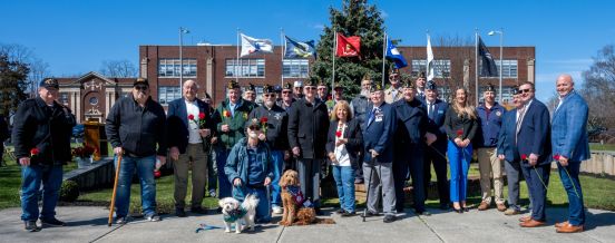 group photo with electeds and veterans in front of memorial