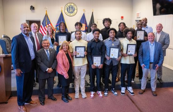 Town Board stands in group photo with basketball players
