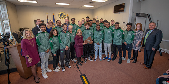 Supervisor Carpenter and the Islip Town Board pose for a photo in the Town Board Room with the Brentwood Varsity Basketball team