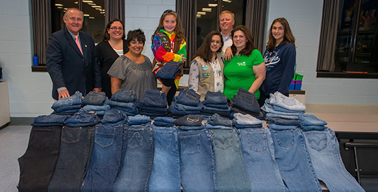 Girl Scouts and representatives from the Town of Islip Youth Bureau stand with a pile of jeans