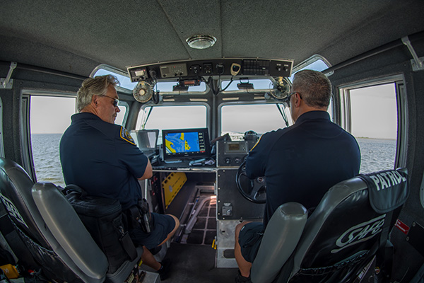 Islip Town Harbormasters stand inside their patrol boat as they cruise the wateraways around Islip