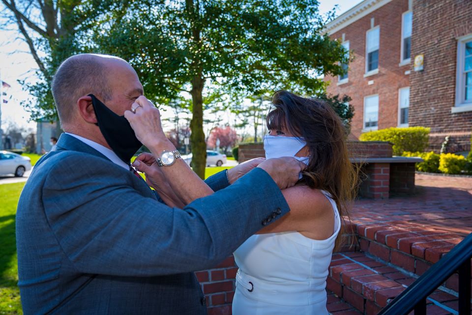 The bride and groom both prepare to lift eachothers masks for the first kiss