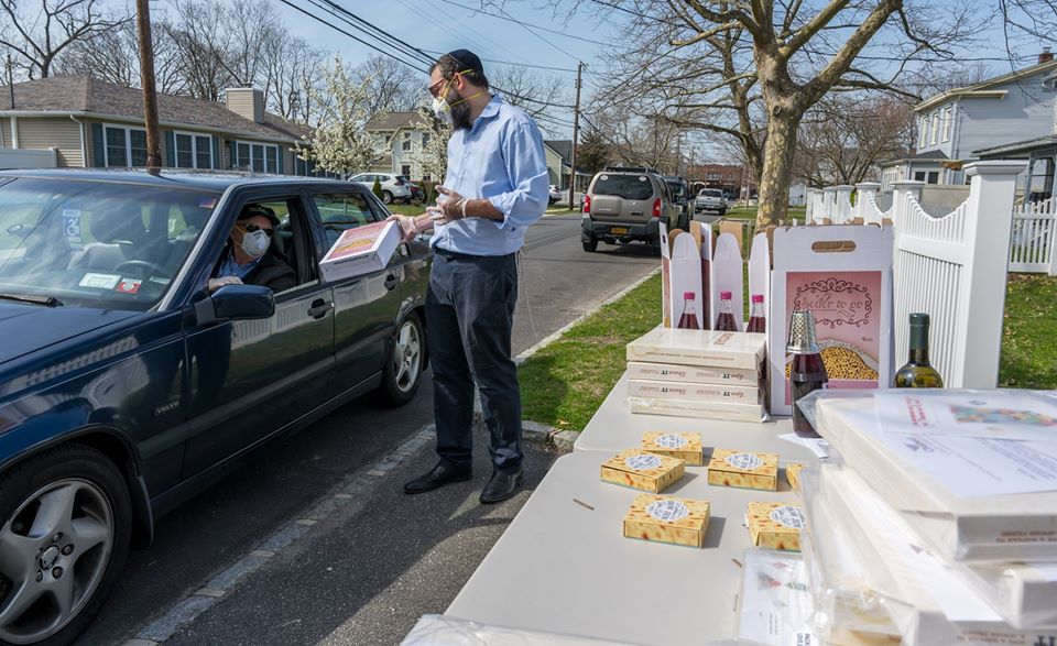 rabbi stands by item stand, hands out box