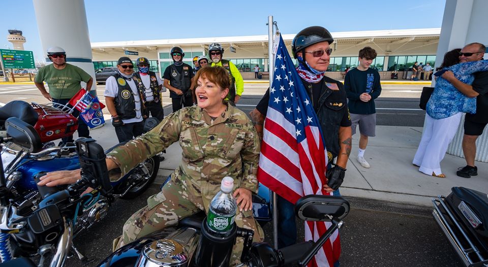 Commander sit on motorcycle next to US Navy vet
