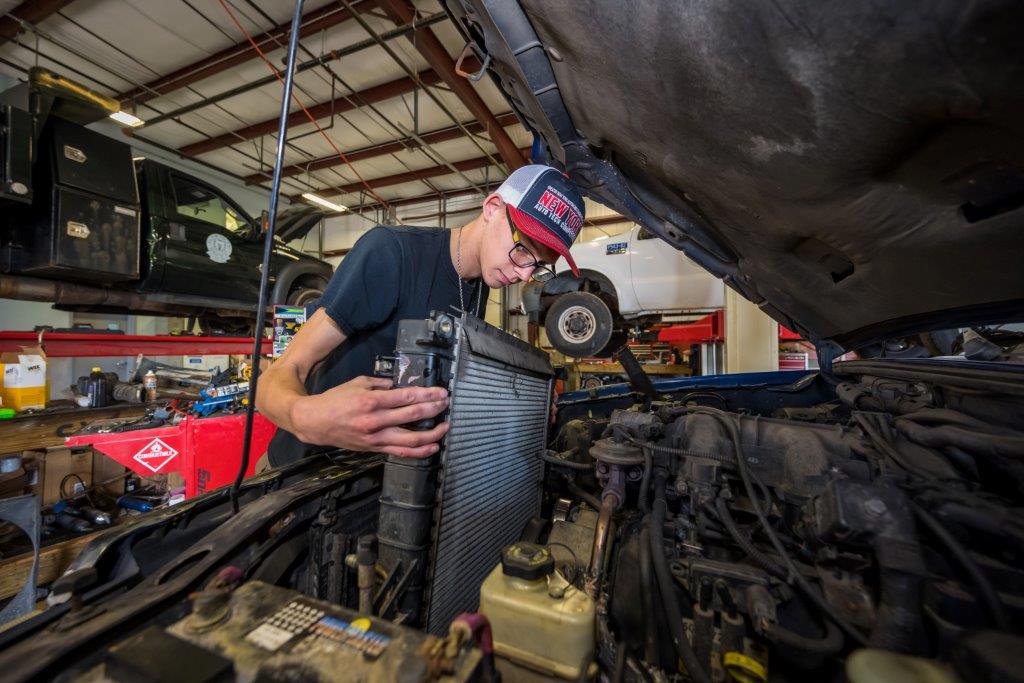 A student places a new air filter into a vehicle.