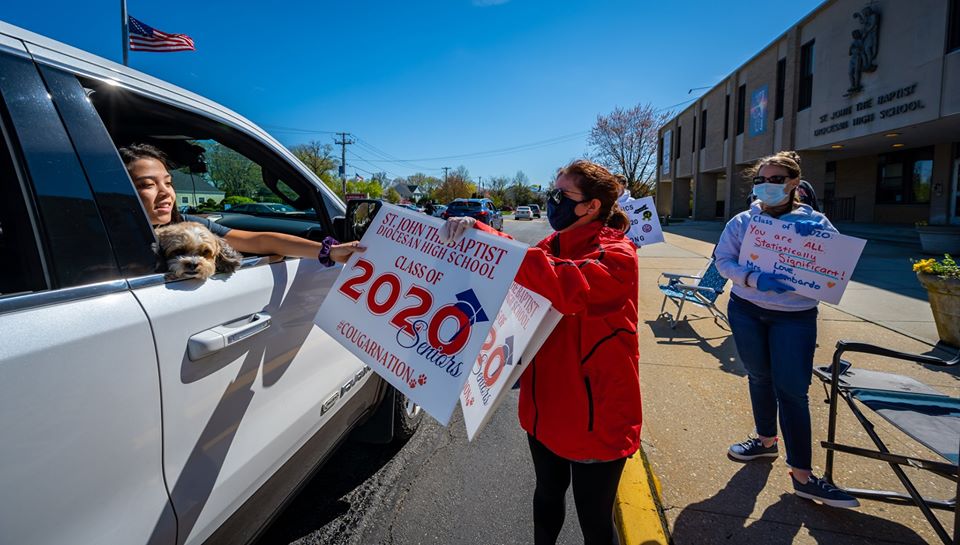 staff in ppe hand out 2020 congratulatory signs