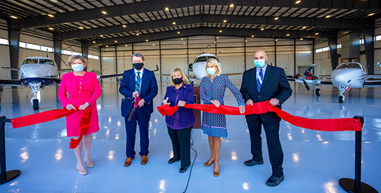 Town officials stand in the new hangar at Islip MacArthur Airport. They are cutting a ribbon to launch the unveiling of the new 32,000 sq facility.