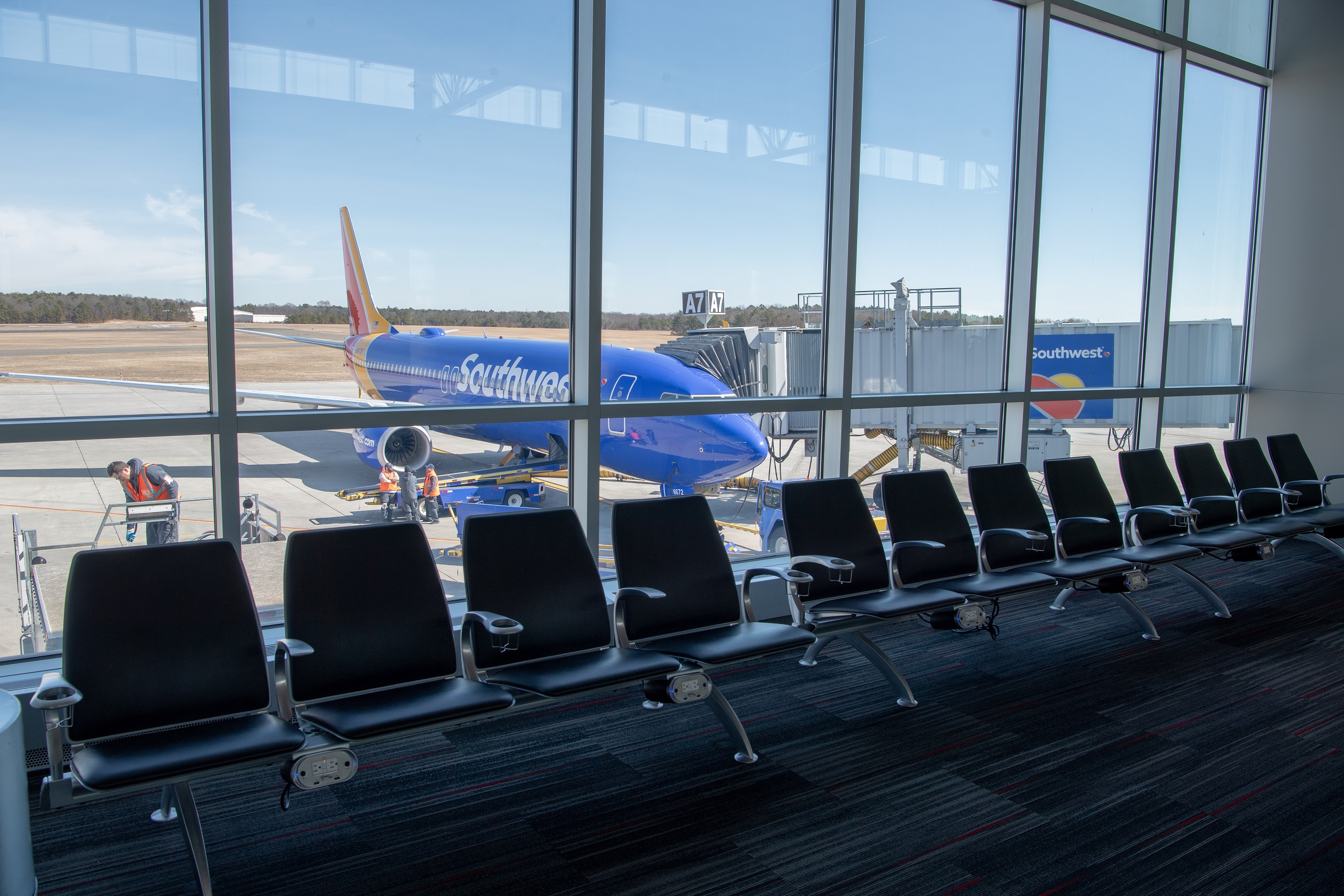  An image of a row of seats in front of terminal glass, a southwest airplane at the terminal on the other side.