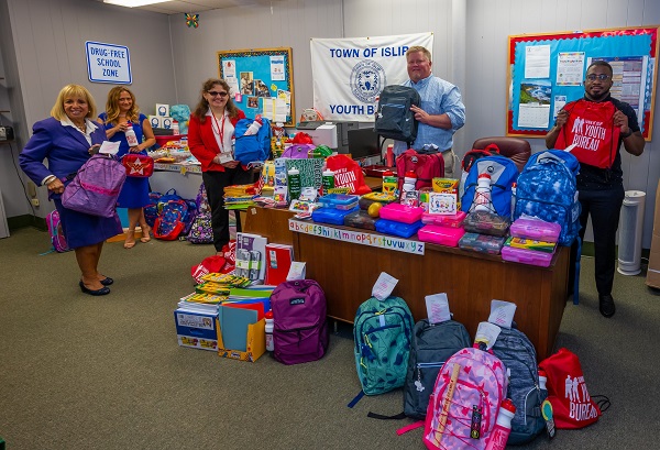supervisor carpenter and members of the Islip Town Youth Bureau display the many school supplies donated by businesses and members within the community for families in need in the Town