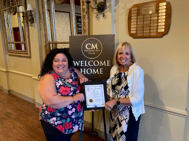 Supervisor Carpenter stands with Alyse Arpino, Executive Director of CM Performing Arts. The supervisor presents Alyse with a certificate to commemorate the re-opening of the performing arts center since the COVID-19 pandemic began.