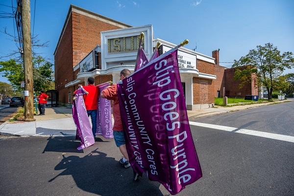 Members of the community and Youth Enrichment Services carry purple Islip Goes Purple flags that they will hang along the main roadways in Islip