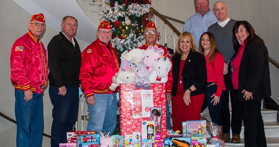 Supervisor Carpenter, Councilman Cochrane and Youth Bureau Director stand in front of a christmas tree surrounded by toys donated by local marines