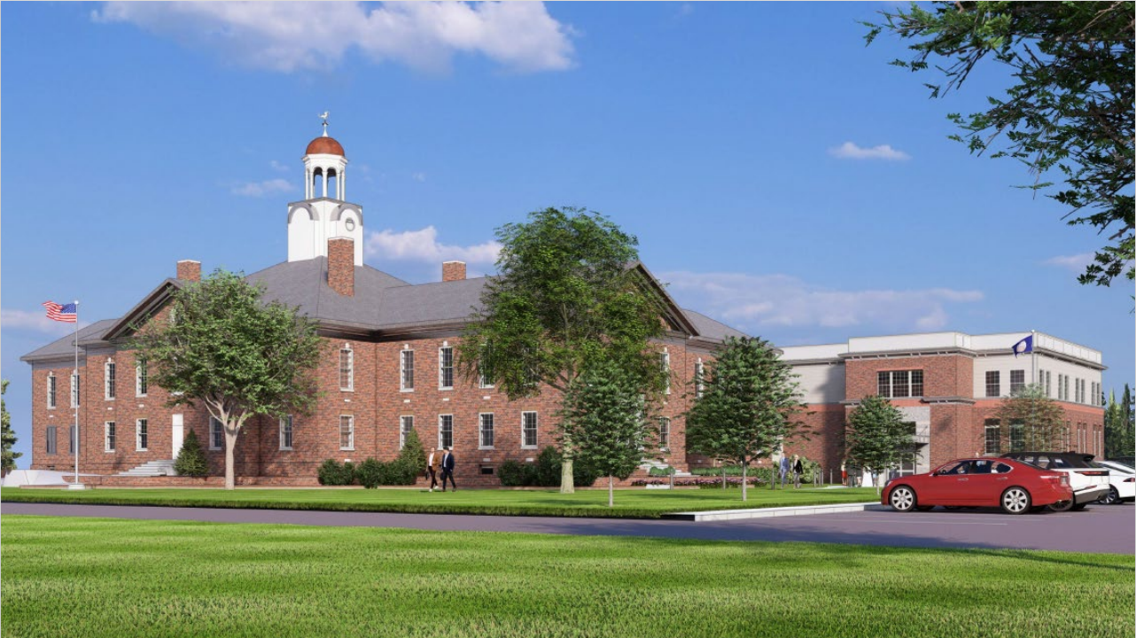 A stately brick Town Hall Annex with a white cupola stands against a blue sky.