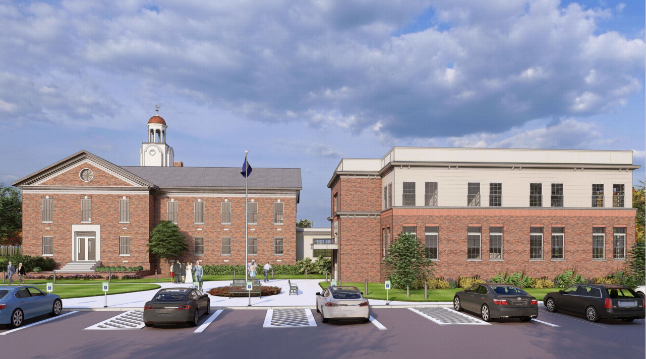 B EditA front-facing view of the Town Hall Annex showing the building's symmetrical design, with a parking area and illustrated pedestrians in the foreground.