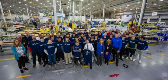 Students and Manufacturing team in a wide shot on factory floor with Supervisor Carpenter