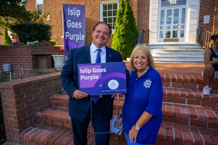 Suffolk County District Attorney Ray Tierney poses with Islip Supervise Angie Carpenter with Islip Goes Purple sign