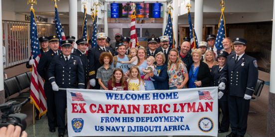 Family, friends and members of the Bay Shore Fire Dept. gather infront of the welcome home eric lyman sign