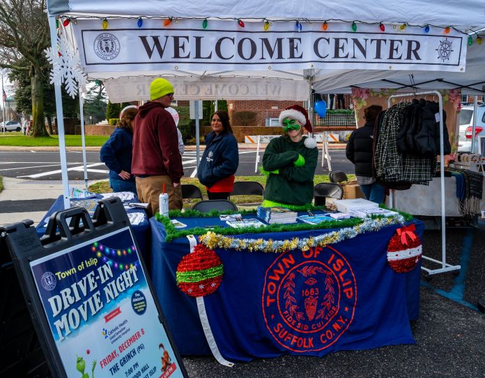 Islip Welcome Booth at Holiday Market with seal, movie night flyer and worker dressed in grinch face