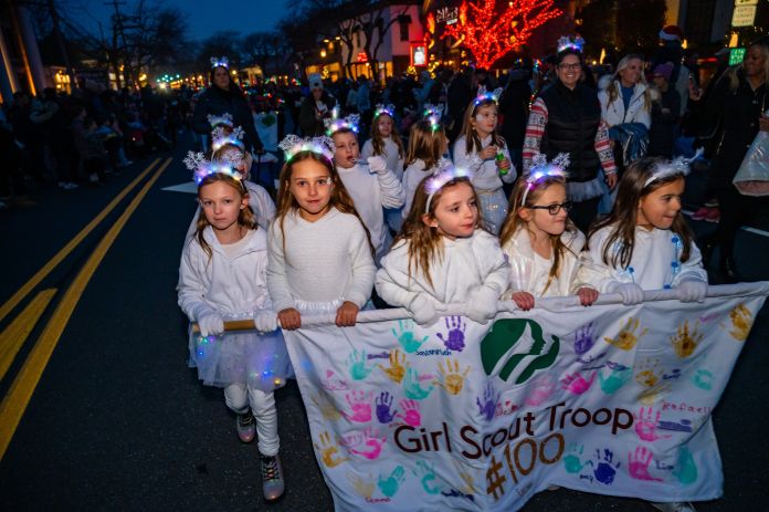 Girl Scout Troop #100 all in white and snowflake headgear march in parade
