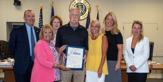 Town Supervisor Angie Carpenter and the Islip Town Board stand near Gary Stack holding his Citation of Recognition in the Town Board Room before the Town Board meeting attendants.