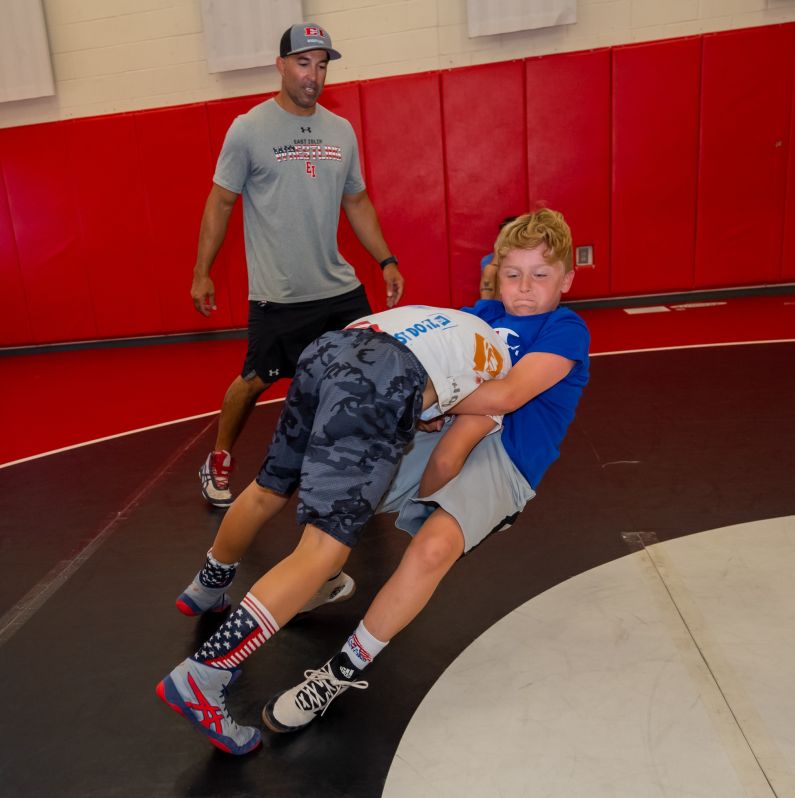 Wrestlers in mid takedown, as falling wrestler grapples to turn an advantage 