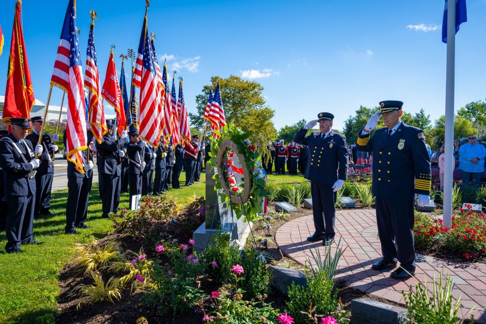 Memorial wreath saluted with flags held by officers to the side.