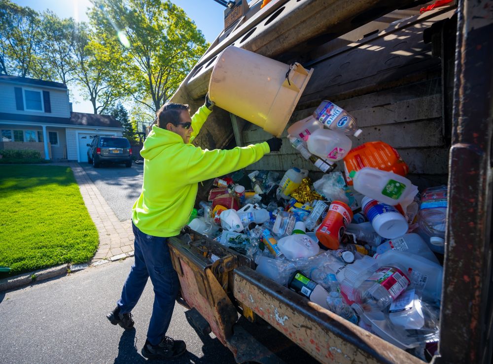 crew member pours recycleables into back of truck