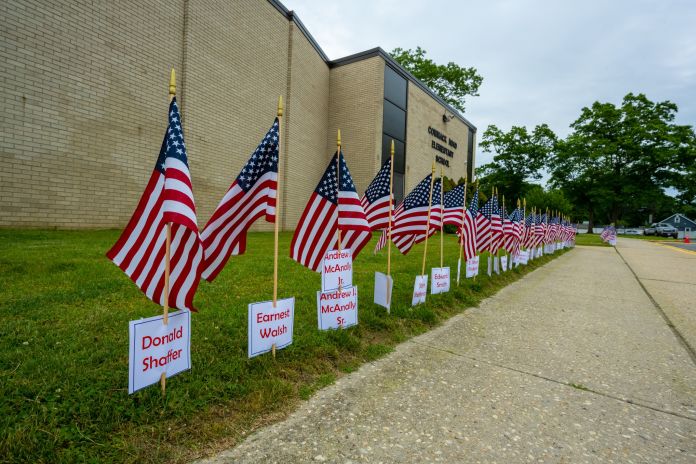 Flags with memorial names on them line the side lawn of the school