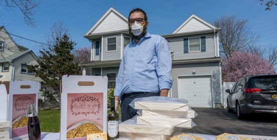 Rabbi in mask stands over passover items