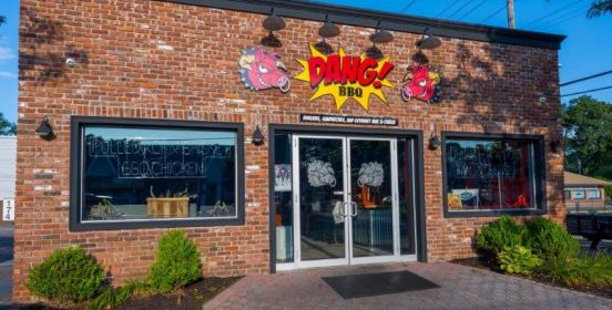 Storefront image of Dang! BBQ with classic comic book action bubble logo above the glass double doors.