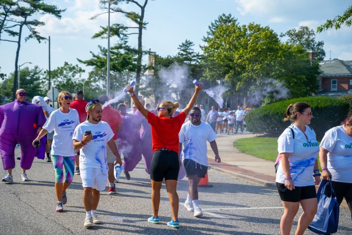 Attendant sprays runners with purple dye as part of the color fun run as they pass the finish line