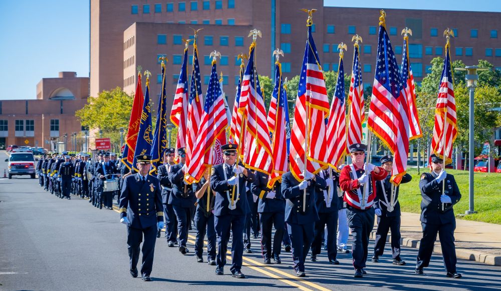 Fire Department Personnel march carrying American Flags