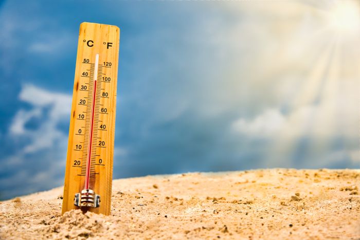 Thermometer in sand with red rising