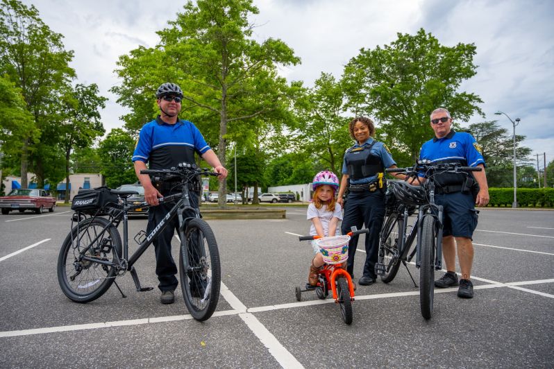 Officers with Bikes take group photo with girl on tricycle