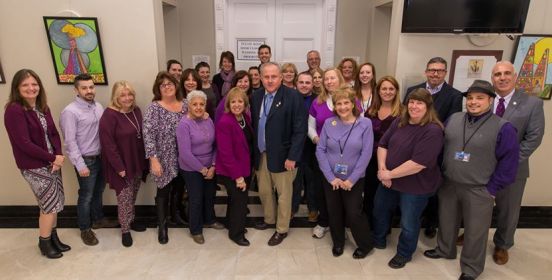 Town Employees alongside Supervisor Carpenter pose in purple in the hall outside the Town Board Room, picture from 2019.