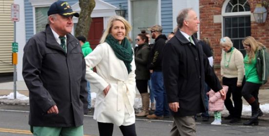 Councilman Cochrane, councilwoman Mullen and Legislator Cilmi walk down the streets, dressed in green as bystanders look on.