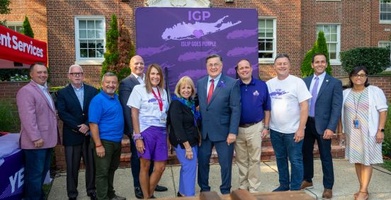 Local and Elected Officials in group photo in front of giant Islip Goes Purple Logo Board