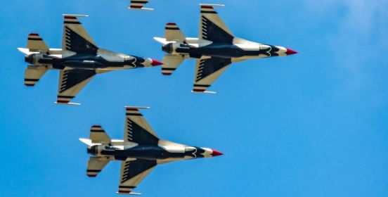 thunderbirds fly in unison through a jet blue sky