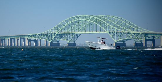 An image of a motor boat crusing under the Robert Mosses bridge.