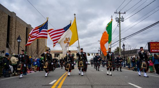 USA, Irish flags held by bannermen in traditional garb