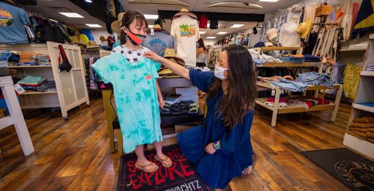 store attendant holds up shirt size to girl