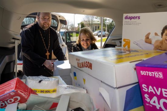 Supervisor Carpenter and Father Victor unload car full of donations