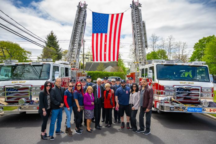 Supervisor with friends and family under American Flag flown between two FD ladders