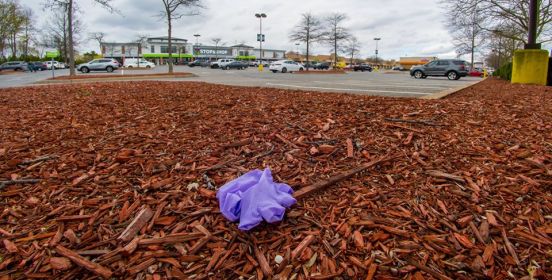 A purple latex glove thrown on the ground in the parking lot.