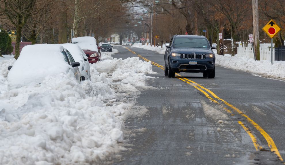 Cars on side of road covered in snow while passing vehicle veers over median to pass safely