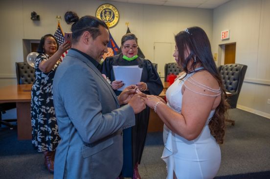 Groom places the ring on Bride