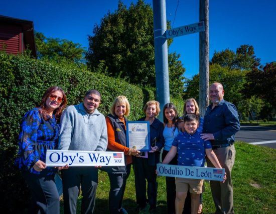 Group photo with family holding sign reading Oby's Way