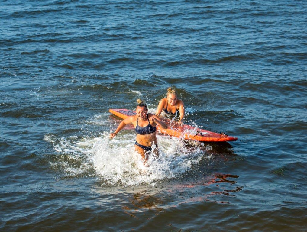both female lifeguard return to shore, rushing to leap out of the water asap